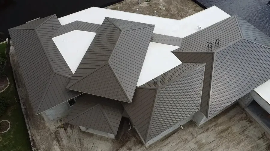 Complex hip roof with standing seam metal and flat roof combination aerial drone view Fort Myers FL